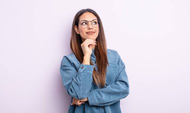 Güzel İspanyol bir kadın düşünceli, meraklı ya da hayal kuruyor, hayal kuruyor ve mekanı kopyalamak için yukarı bakıyor.