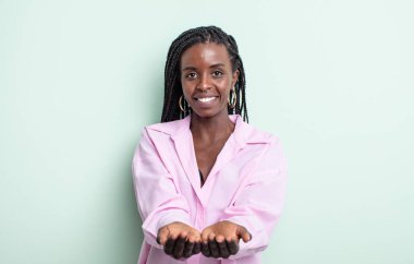 siyah güzel kadın mutlu bir şekilde gülümsüyor arkadaş canlısı, kendine güvenen, olumlu bakışlı, bir nesne ya da konsept sunan ve gösteren