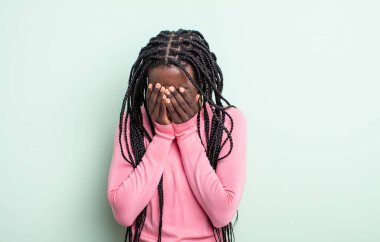 Siyah güzel bir kadın üzgün, hayal kırıklığına uğramış, gergin ve depresif, iki eliyle yüzünü örten, ağlayan