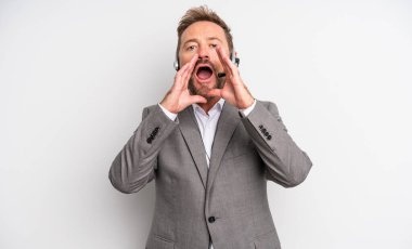 Orta yaşlı, yakışıklı, mutlu bir adam. Elleri ağızda, kocaman bağırıyor. tele pazarlama kavramı