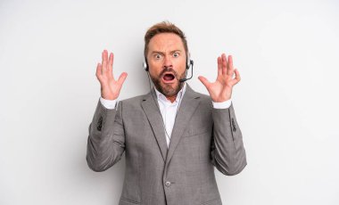 Orta yaşlı yakışıklı adam ellerini havaya kaldırarak bağırıyor. tele pazarlama kavramı