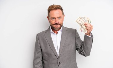 Kafası karışmış ve kafası karışmış orta yaşlı yakışıklı bir adam. Dolar banknotları konsepti