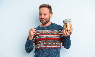 Orta yaşlı yakışıklı adam kibirli, başarılı, pozitif ve gururlu görünüyor. kurabiye şişesi