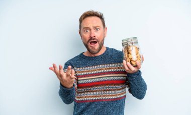 Orta yaşlı yakışıklı adam umutsuz, sinirli ve stresli görünüyor. kurabiye şişesi