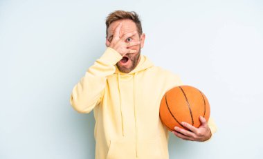 Orta yaşlı yakışıklı bir adam şok olmuş, korkmuş ya da korkmuş görünüyor. Yüzü elle kapatılmış. Basketbol konsepti