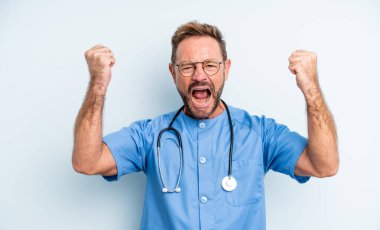 Orta yaşlı yakışıklı adam sinirli bir ifadeyle agresif bir şekilde bağırıyor. hemşire konsepti