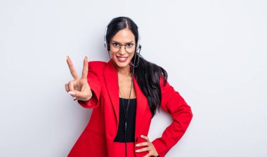 Güzel İspanyol bir kadın gülümsüyor ve mutlu görünüyor, zafer ya da barış işareti yapıyor. tele pazarlama kavramı