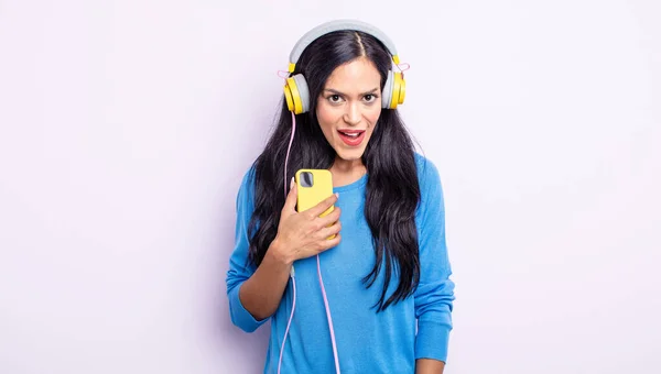 Όμορφη Ισπανίδα Που Δείχνει Σοκαρισμένη Έκπληκτη Έννοια Smartphone Και Ακουστικά — Φωτογραφία Αρχείου