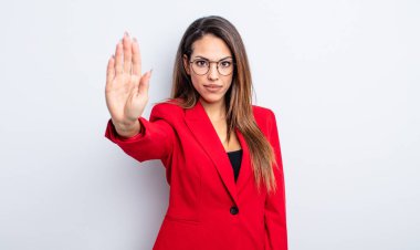 Güzel İspanyol kadın ciddi görünüyor. Avuç içinin açık olduğunu gösteriyor. Durdurma hareketi yapıyor. İş kadını kavramı