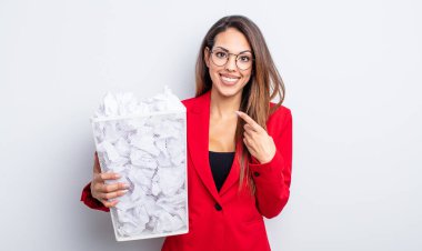 Güzel İspanyol kadın neşeyle gülümsüyor, mutlu hissediyor ve bir tarafı işaret ediyor. kağıt toplar başarısızlık konsepti