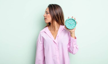 Profil görünümlü güzel İspanyol kadın hayal kuruyor, hayal kuruyor ya da hayal kuruyor. Alarm saati kavramı