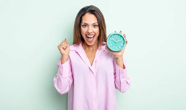 かなりヒスパニックな女はショックを受けて笑って成功を祝ってる 目覚まし時計のコンセプト — ストック写真