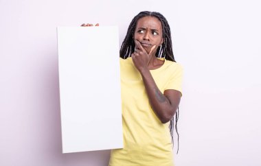 Güzel siyah kadın düşünüyor, kuşkulu ve şaşkın hissediyor. boş tuval konsepti