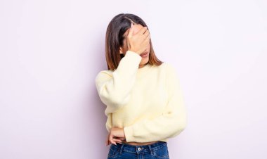 Güzel İspanyol kadın stresli, utanmış ya da üzgün görünüyor, baş ağrısı var, yüzünü elle kapatıyor.