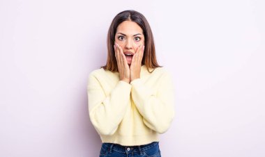 Güzel İspanyol kadın şok olmuş ve korkmuş hissediyor, ağzı açık ve elleri yanaklarında korkmuş görünüyor.