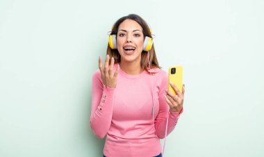 Tatlı İspanyol kadın umutsuz, sinirli ve stresli görünüyor. akıllı telefon ve kulaklık kavramı