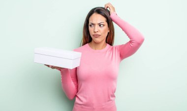 Kafası karışık, kafası karışık, kaşınan bir İspanyol kadın. beyaz kutu paketleme kavramı