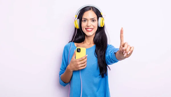Mooie Spaanse Vrouw Glimlachend Vriendelijk Uitziend Nummer Één Tonend Smartphone — Stockfoto
