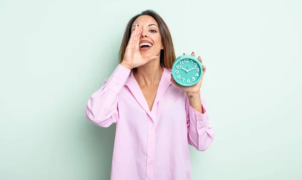 かなりヒスパニックな女は幸せを感じ口の横で大きな声を出す 目覚まし時計のコンセプト — ストック写真