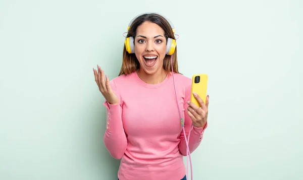 Pretty Hispanic Woman Feeling Happy Astonished Something Unbelievable Smartphone Headphones — Stock Photo, Image