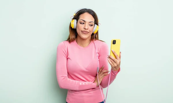 Pretty Hispanic Woman Shrugging Feeling Confused Uncertain Smartphone Headphones Concept — Stock Photo, Image