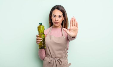 Güzel İspanyol kadın ciddi görünüyor. Avuç içinin açık olduğunu gösteriyor. Durdurma hareketi yapıyor. Zeytin yağı kavramı