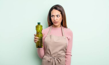 Güzel İspanyol bir kadın üzgün, üzgün ya da kızgın hissediyor ve yan tarafa bakıyor. Zeytin yağı kavramı