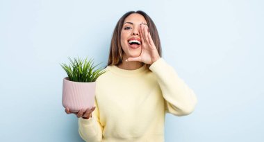 Güzel İspanyol bir kadın kendini mutlu hissediyordu, elleri ağzının kenarında bağırıyordu. ev bitkisi kavramı