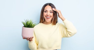 Oldukça İspanyol bir kadın mutlu, şaşkın ve şaşırmış görünüyor. ev bitkisi kavramı