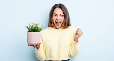 Oldukça İspanyol bir kadın şoke olmuş, gülüyor ve başarıyı kutluyor. ev bitkisi kavramı