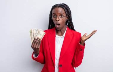 Güzel siyah kadın şaşırmış ve şok olmuş görünüyor. Çenesi düşmüş ve elinde bir nesne tutuyor. Dolar banknotları konsepti