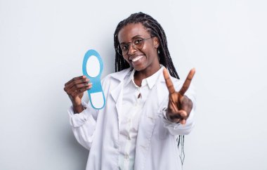 Güzel siyah kadın gülümsüyor ve arkadaş canlısı görünüyor, iki numarayı gösteriyor. podiatrist kavramı