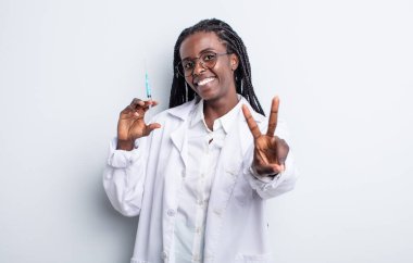 Güzel siyah kadın gülümsüyor ve mutlu görünüyor, zafer ya da barış işareti yapıyor. Sryinge konsepti