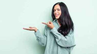 Güzel İspanyol kadın gülümsüyor, mutlu, kaygısız ve tatmin olmuş hissediyor, fotokopi alanındaki konsepte ya da fikre işaret ediyor.