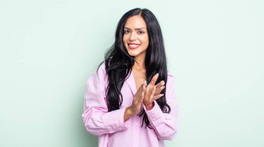 Güzel İspanyol bir kadın mutlu ve başarılı hissediyor, gülümsüyor ve alkışlıyor, alkışlarla tebrik ediyor.