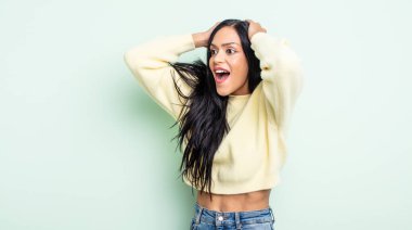 Ağzı açık, korkunç bir hata yüzünden dehşete düşmüş ve şok olmuş bir halde ellerini havaya kaldıran güzel İspanyol bir kadın.