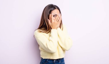 Güzel İspanyol bir kadın korkmuş ya da utanmış hissediyor. Gözleri yarı kapalı ya da elleri kapalı gözetliyor.