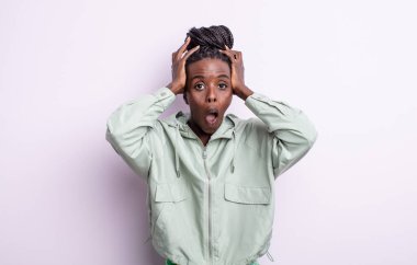 Siyah, güzel bir kadın heyecanlı ve şaşırmış görünüyor, ağzı açık, elleri başının üstünde, kendini şanslı hissediyor.