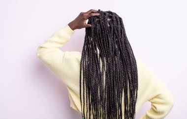 Siyah güzel bir kadın bilgisiz ve kafası karışık, bir çözüm düşünüyor, eli kalçasında, diğeri kafasında, dikiz aynasından.