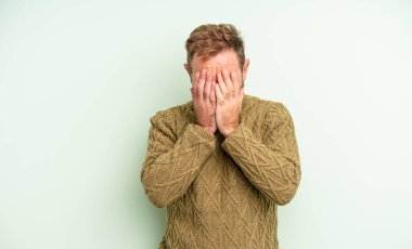 Orta yaşlı, yakışıklı, üzgün, sinirli ve depresif bir adam. İki eliyle yüzünü kapatıyor, ağlıyor.