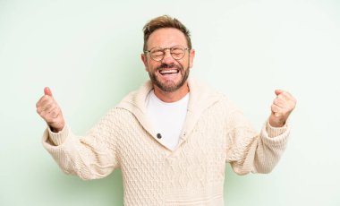 Orta yaşlı yakışıklı adam çok mutlu ve şaşırmış görünüyor, başarıyı kutluyor, bağırıyor ve zıplıyor.