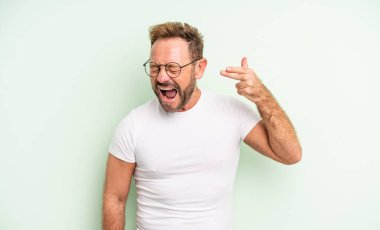 Orta yaşlı, yakışıklı, mutsuz ve stresli görünen bir adam, intihar jesti, elle silah işareti yapıyor, kafasını işaret ediyor.