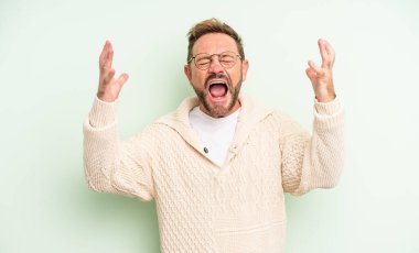 Orta yaşlı yakışıklı adam öfkeyle bağırıyor, stresli hissediyor ve ellerini havaya kaldırıp neden ben diye bağırıyor.