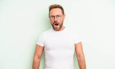 Orta yaşlı yakışıklı adam korkmuş ve şok olmuş hissediyor, ağzı açık şaşkınlık içinde.