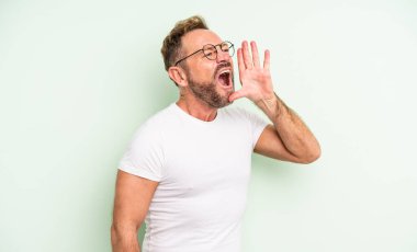 Orta yaşlı, yakışıklı bir adam öfkeyle bağırıyor. Yan taraftaki boşluğu kopyalasın, eli ağzının yanında.