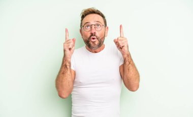 Orta yaşlı, yakışıklı ve ağzı açık bir adam. Şok olmuş ve şaşırmış bir şekilde yukarı bakıyor.