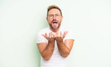 Orta yaşlı yakışıklı adam umutsuz ve sinirli görünüyor, stresli, mutsuz ve sinirli, bağırıyor ve çığlık atıyor.