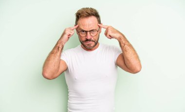 Ciddi ve konsantre görünümlü, beyin fırtınası yapan ve zorlu bir sorunu düşünen orta yaşlı yakışıklı bir adam.