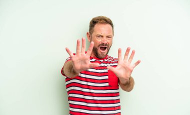 Orta yaşlı yakışıklı bir adam korku ve panik içinde geri çekilip bağırıyor ve kabusa tepki veriyor.