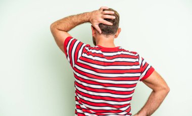 Orta yaşlı yakışıklı bir adam bilgisiz ve kafası karışık hissediyor, bir çözüm düşünüyor, eli kalçasında, diğeri kafasında, dikiz aynasından bakıyor.